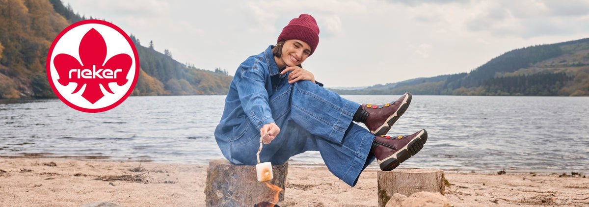 woman toasting marshmallows on a beach - wearing reiker trainers