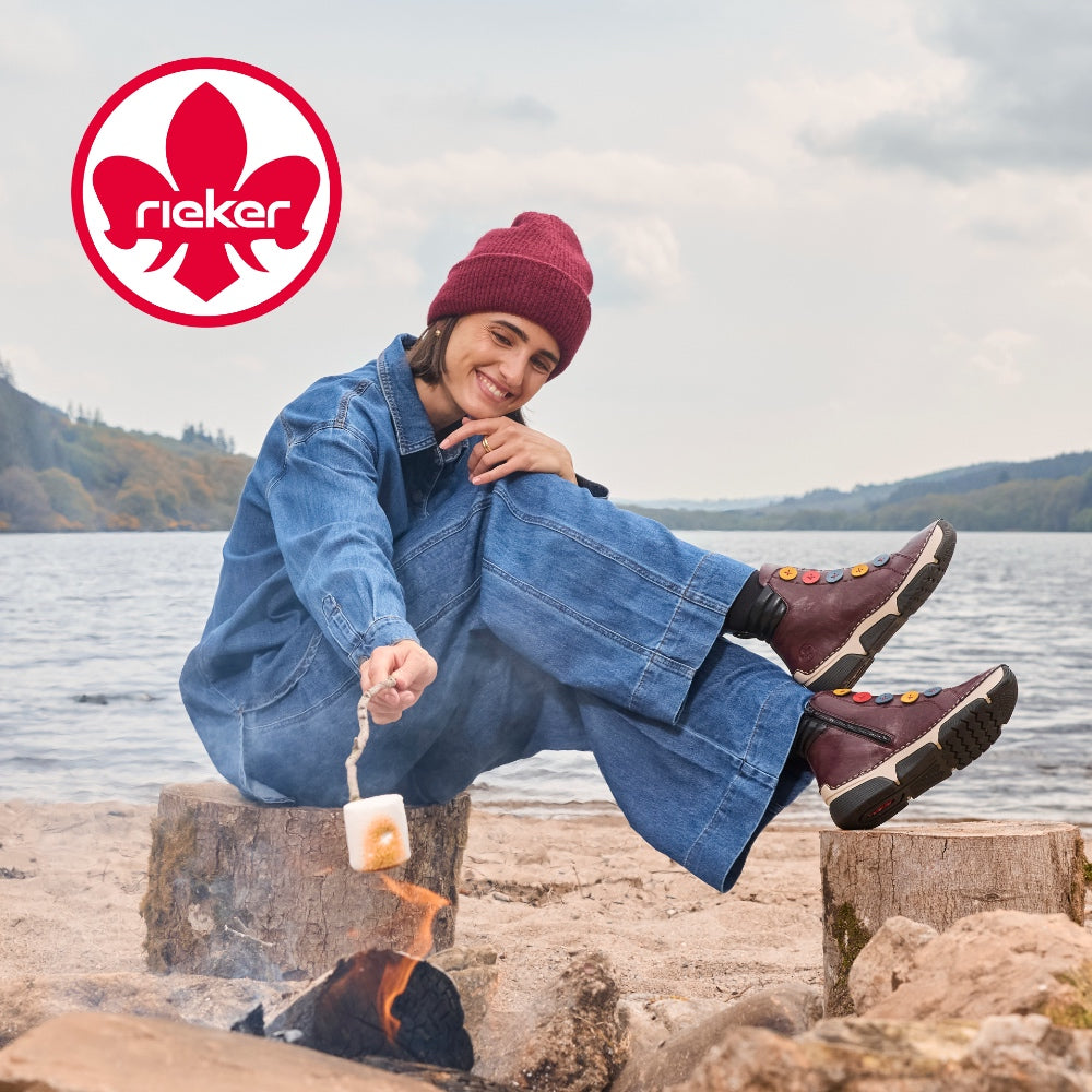 woman toasting marshmallows on a beach - wearing reiker trainers