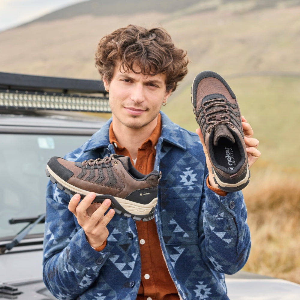 Man holding a pair of brown rieker trainers