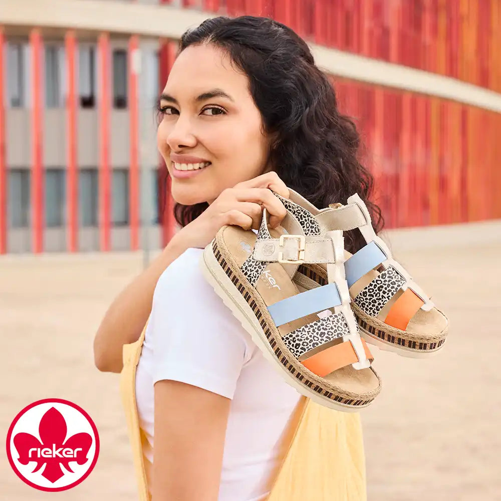 Woman holding a sandal with a colorful background and Rieker logo.