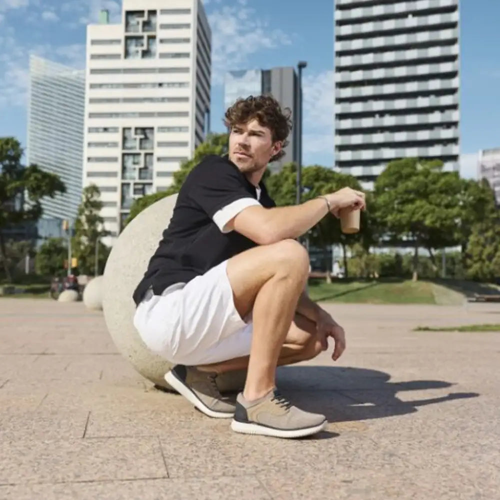 Man squatting in an urban park with modern buildings in the background