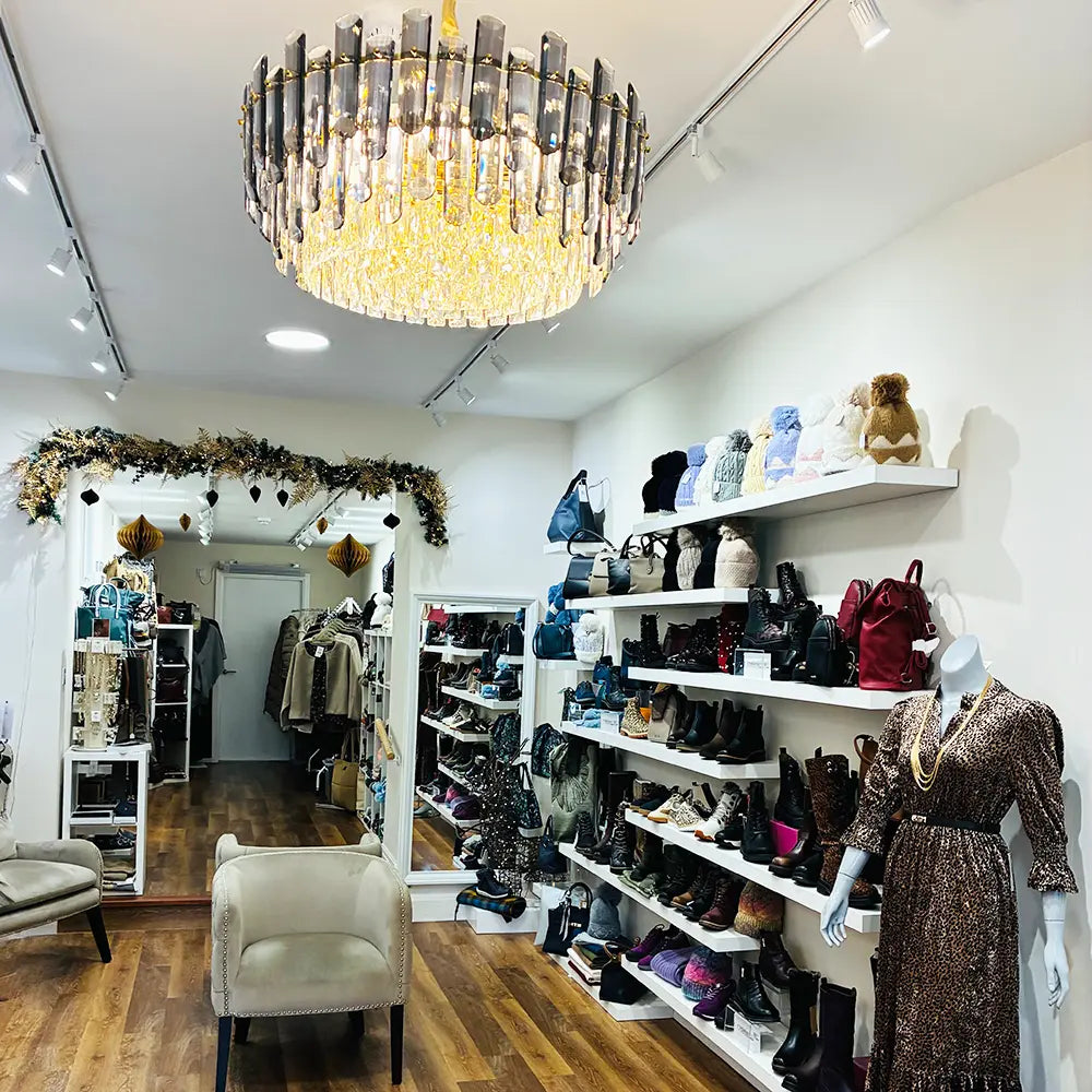 Interior of a fashion store with shelves displaying shoes and clothing, and a chandelier hanging from the ceiling.